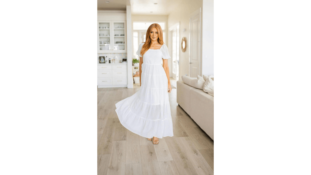 Woman in flowy white summer dress for curvy women standing in living room from Top 10 Summer Outfits for Curvy Women
